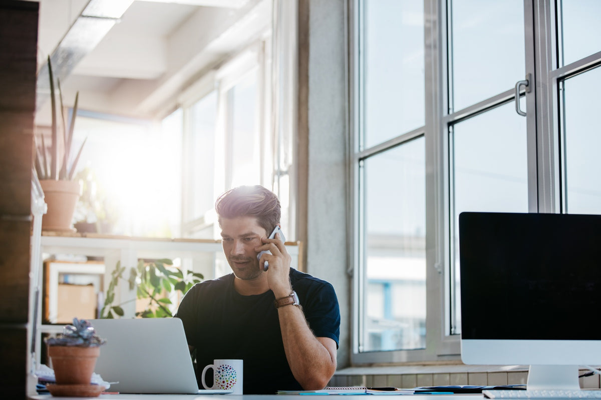 Wireless working. PSD depressed young man sitting at his Desk. Cold calling stock. Businessman with Phone near big Office Window.