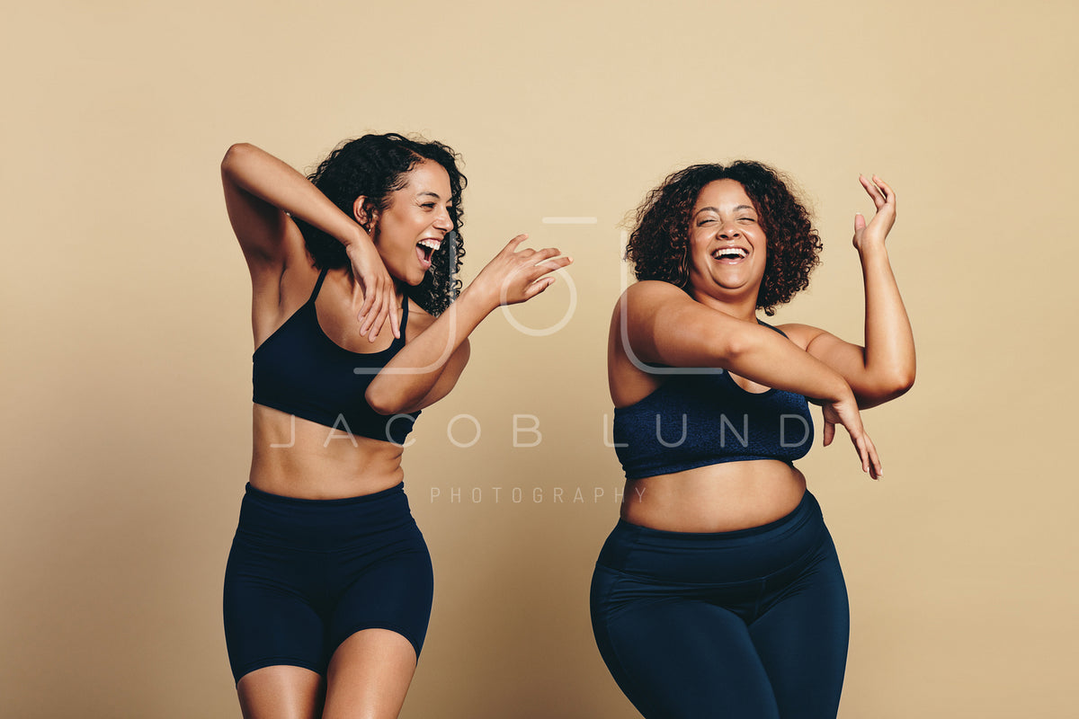 Two happy women sitting on the promenade with beach workout essentials –  Jacob Lund Photography Store- premium stock photo