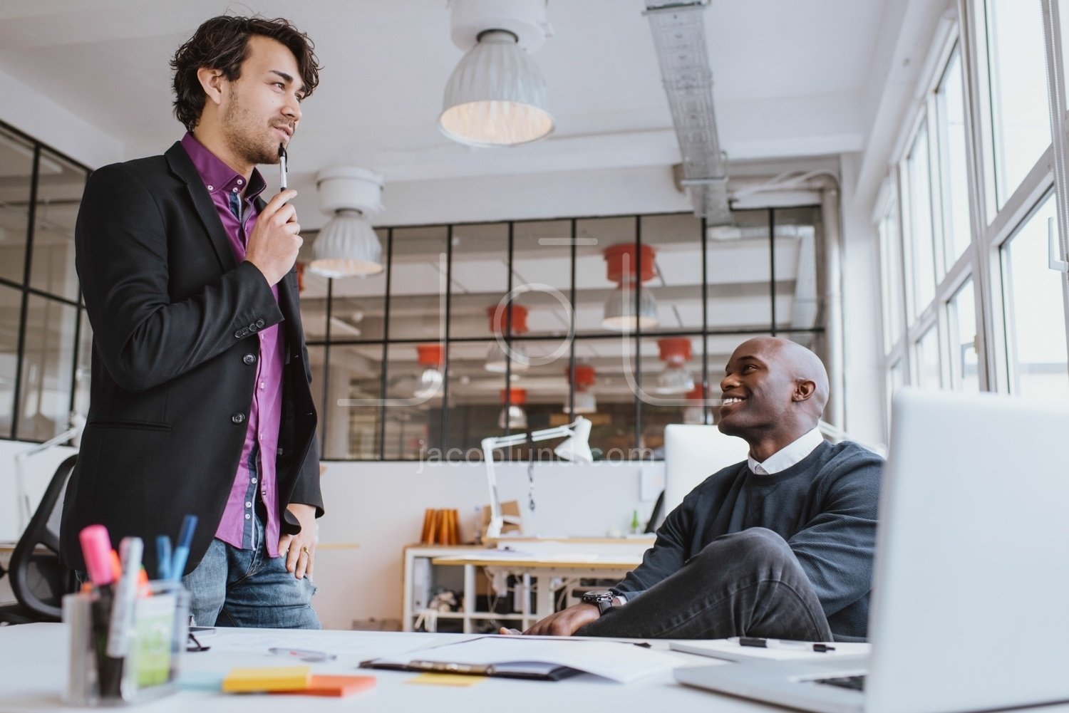 Two young office workers discussing work in office – Jacob Lund Photography  Store- premium stock photo