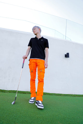 Golf attire outfit for men - black polo, orange cargo pants, and Celine high top sneakers