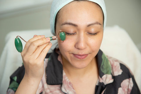 Woman using facial roller self-care beauty ritual