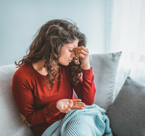 woman sitting on couch with migraine 