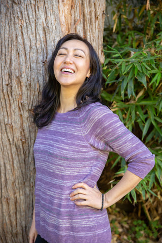 Asian woman laughing in front of a tree