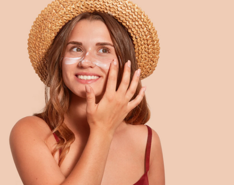 woman applying sunscreen and wearing a hat