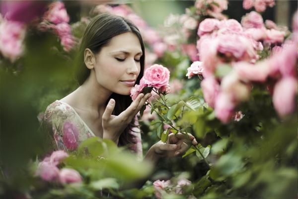 A girl is smelling fragrant roses in lush garden