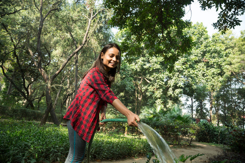 A girl watering trees to keep them healthy