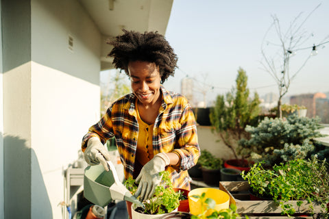 A girl attentively caring for her vibrant potted plants on a balcony