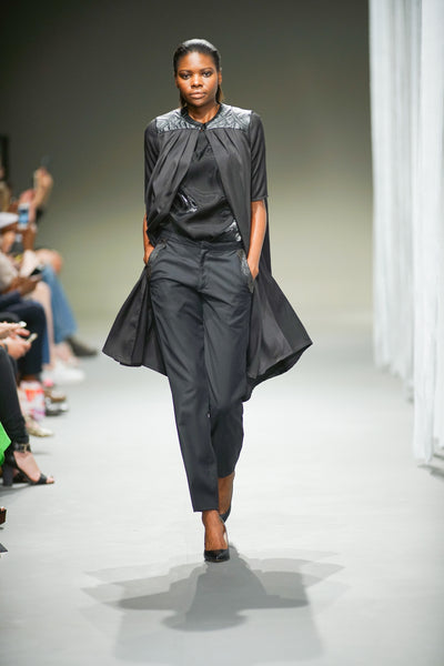 Black short sleeve coat with leather yoke detail over black trousers