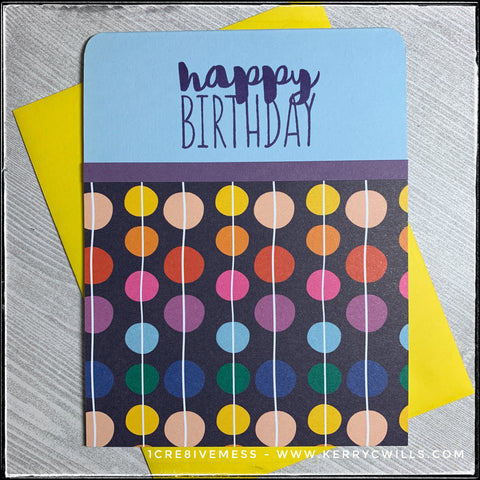 A bright and colorful birthday card, the main characteristic of this design is the repetitive pattern of circular dots connected by a thin white line. As if strands of beads, these colorful circles fill the bottom portion of the card front against a dark blue background which is layered on a sky blue card base. A thin horizontal strip of purple cardstock runs along the card base, directly under the sentiment "happy birthday" which is stamped in dark blue ink. The upper corners of the card have been rounded and a bright yellow envelope is shown - and is included. 