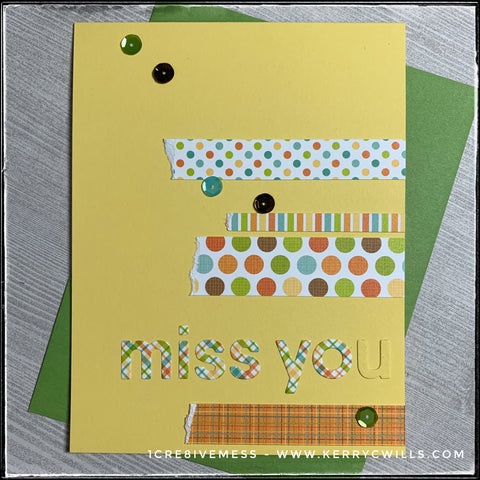 Coordinating colors and a mix of geometrical patterns add detail to this handmade card with a miss you sentiment. The words "miss you" have been die-cut from plaid patterned paper and four additional strips have been stacked to add detail. Patterns on the strips include stripes, plaid, and polka dots in two sizes. One end of the patterned strips has been purposely torn. A smattering of colored sequins add a little dimension. A green envelope is layered beneath the card and is included. 