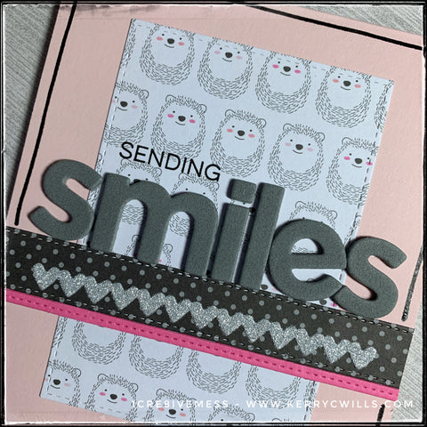 An up close, detailed view of the background pattern full of smiling hedgehogs as well as the die-cut and stamped words combining to create the sentiment, "sending smiles." 