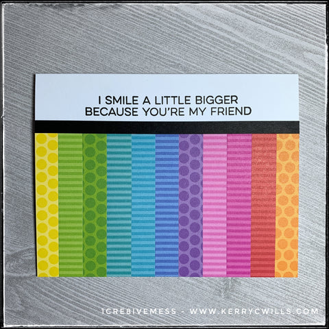 The flat-lay view of this friendship inspired handmade card shows a rainbow full of stripes and polka dots. The stamped sentiment reads "I smile a little bigger because you're my friend."