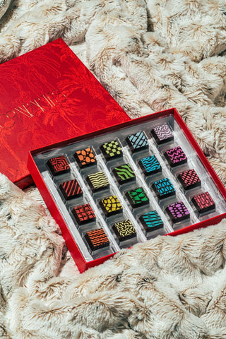 An opened red box of Compartes chocolates sitting on a cream colored rug