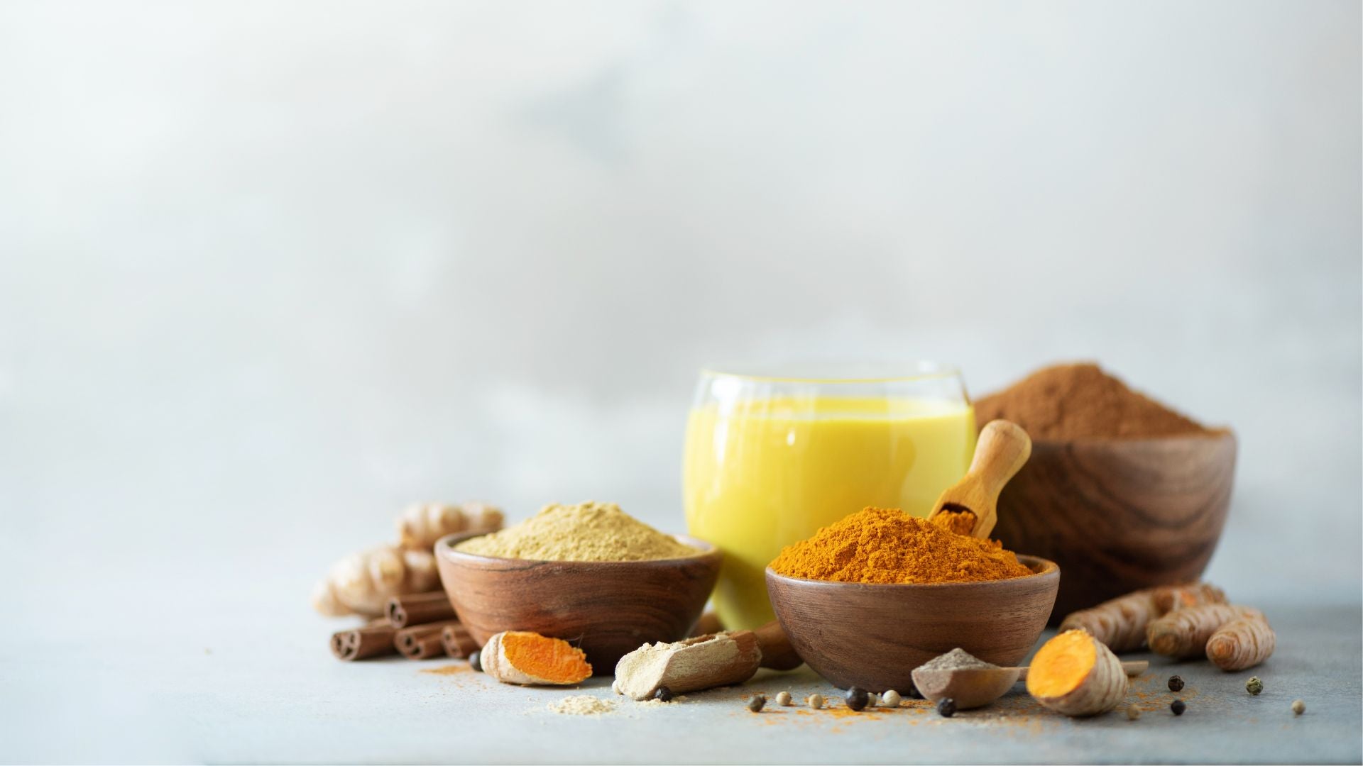 Collombatti Naturals Turmeric Chai in a glass surrounded by herbs and spices