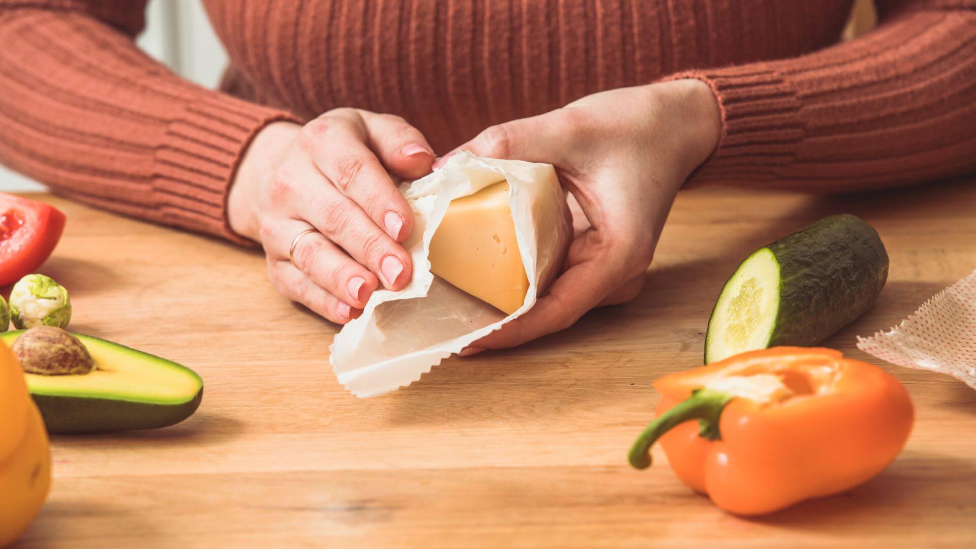 Collombatti Naturals Beeswax Wraps FAQ picture of someone wrapping some hard cheese in a beeswax wrap