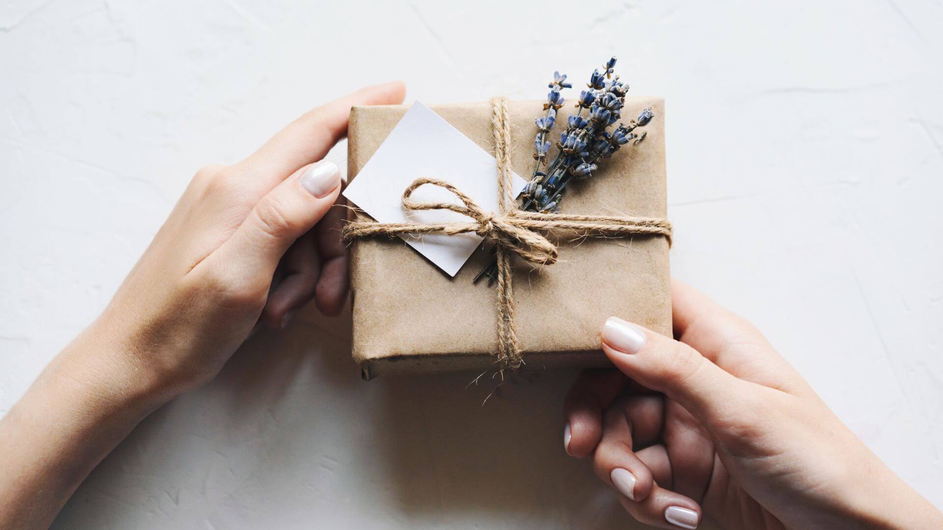 Collombatti Naturals Handmade and ecofriendly christmas gifts picture of a womans hands holding a gift wrapped in brown paper and decorated with lavender