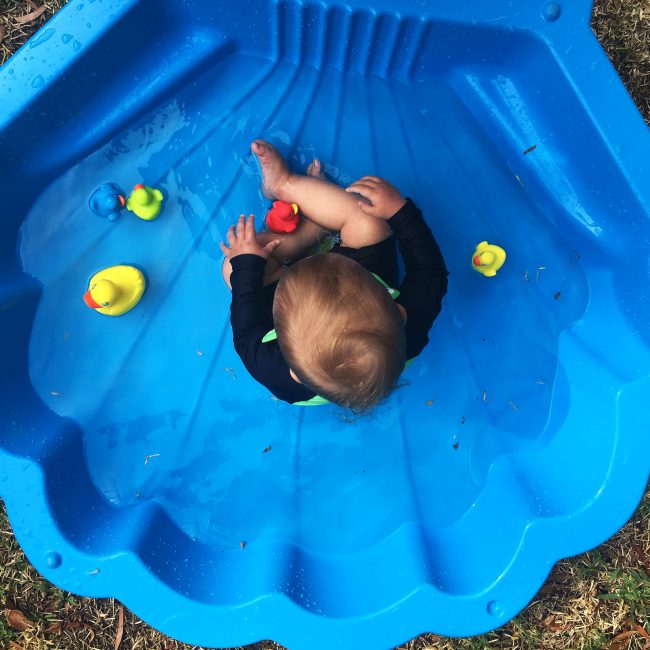 A toddler boy is playing Playgro Colorful Rubber duckie on the outdoor pool