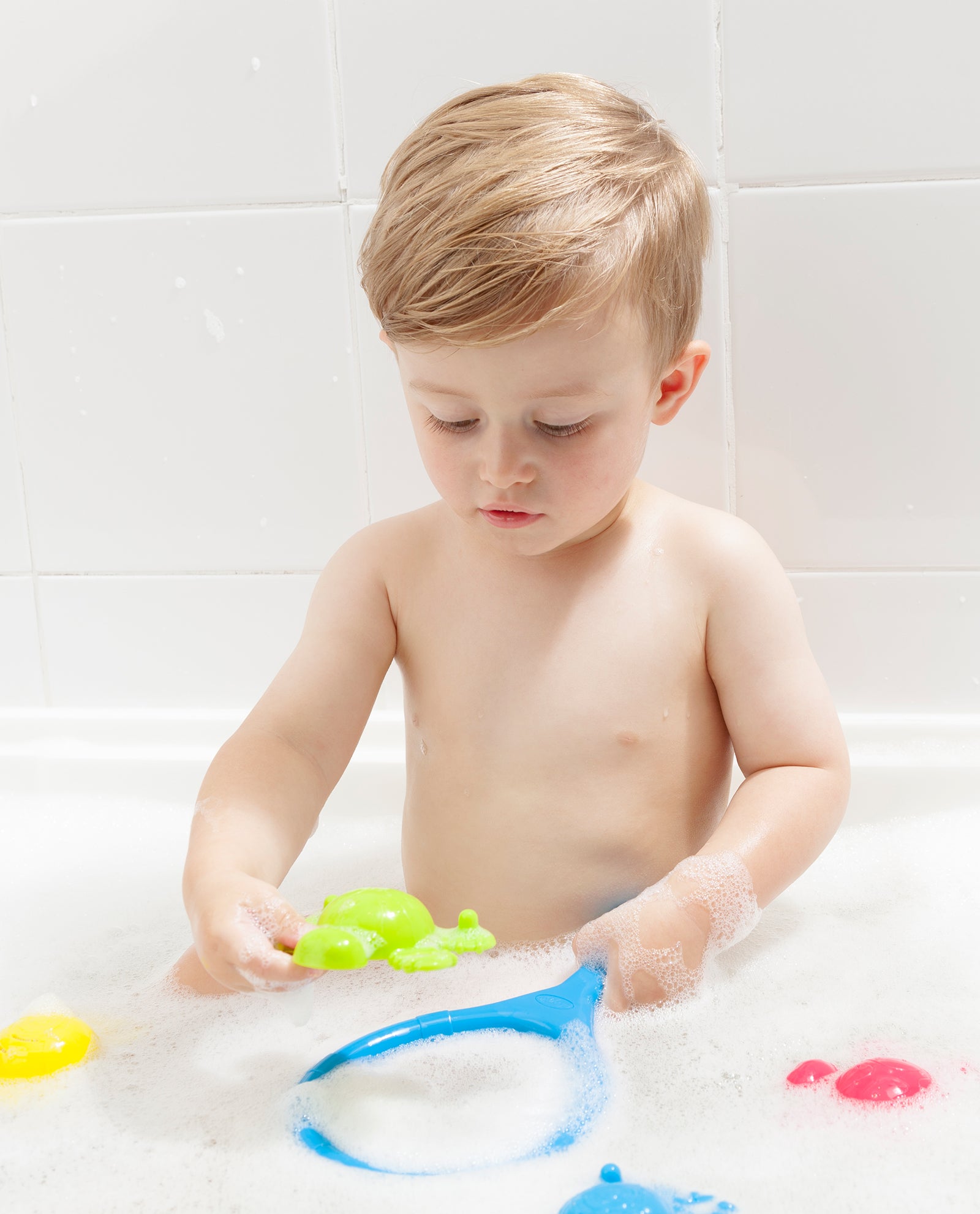 Toddler boy is holding Playgro Scoop and catching Splash Bath toys during his bath time