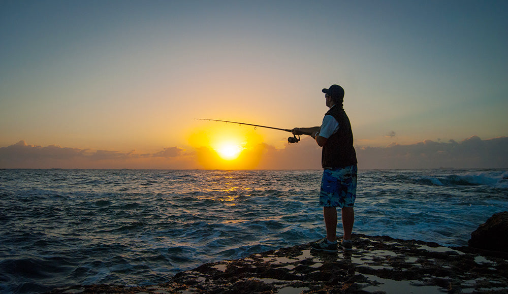 Close up of a man's hand holding a fishing rod. Sunset soft light