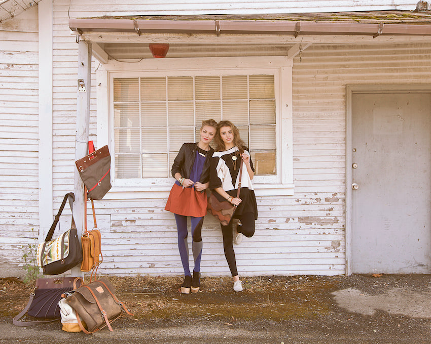 Two girls on a road trip standing outside of an abandoned building.