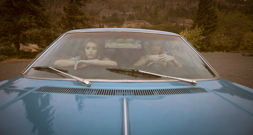 Two best friends in an old car going on a road trip.