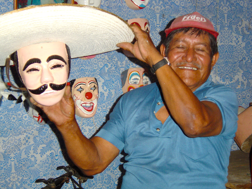 Mexican mask maker holding up a traditional Mexican mask.