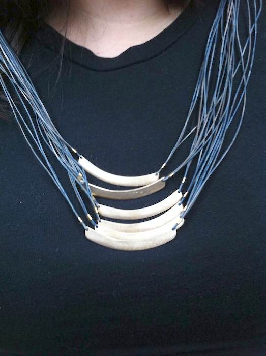 Hayden moon necklace layered several times on a black shirt.