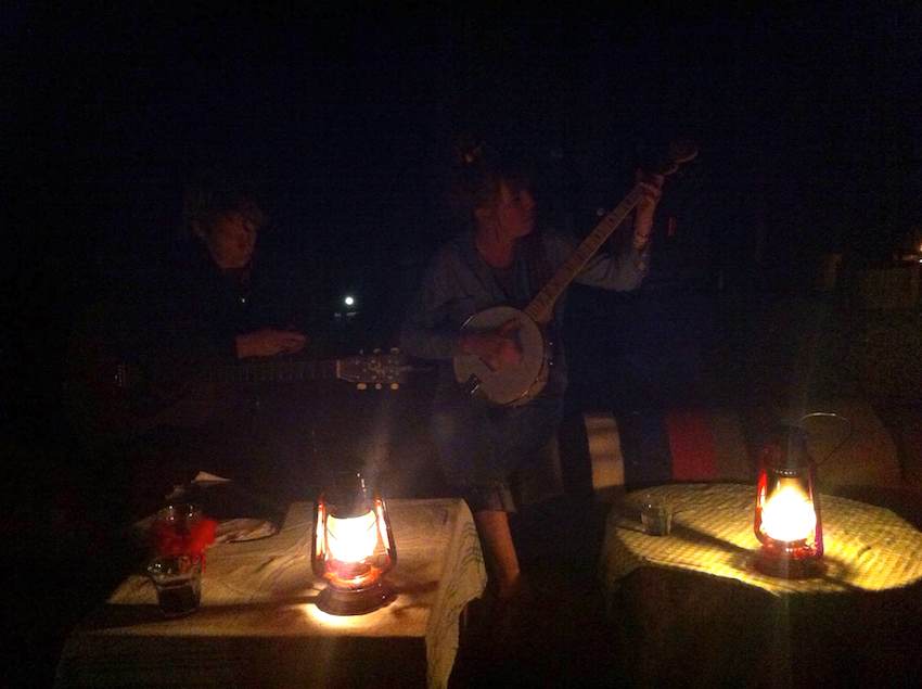 Ladies playing banjos around a campfire.