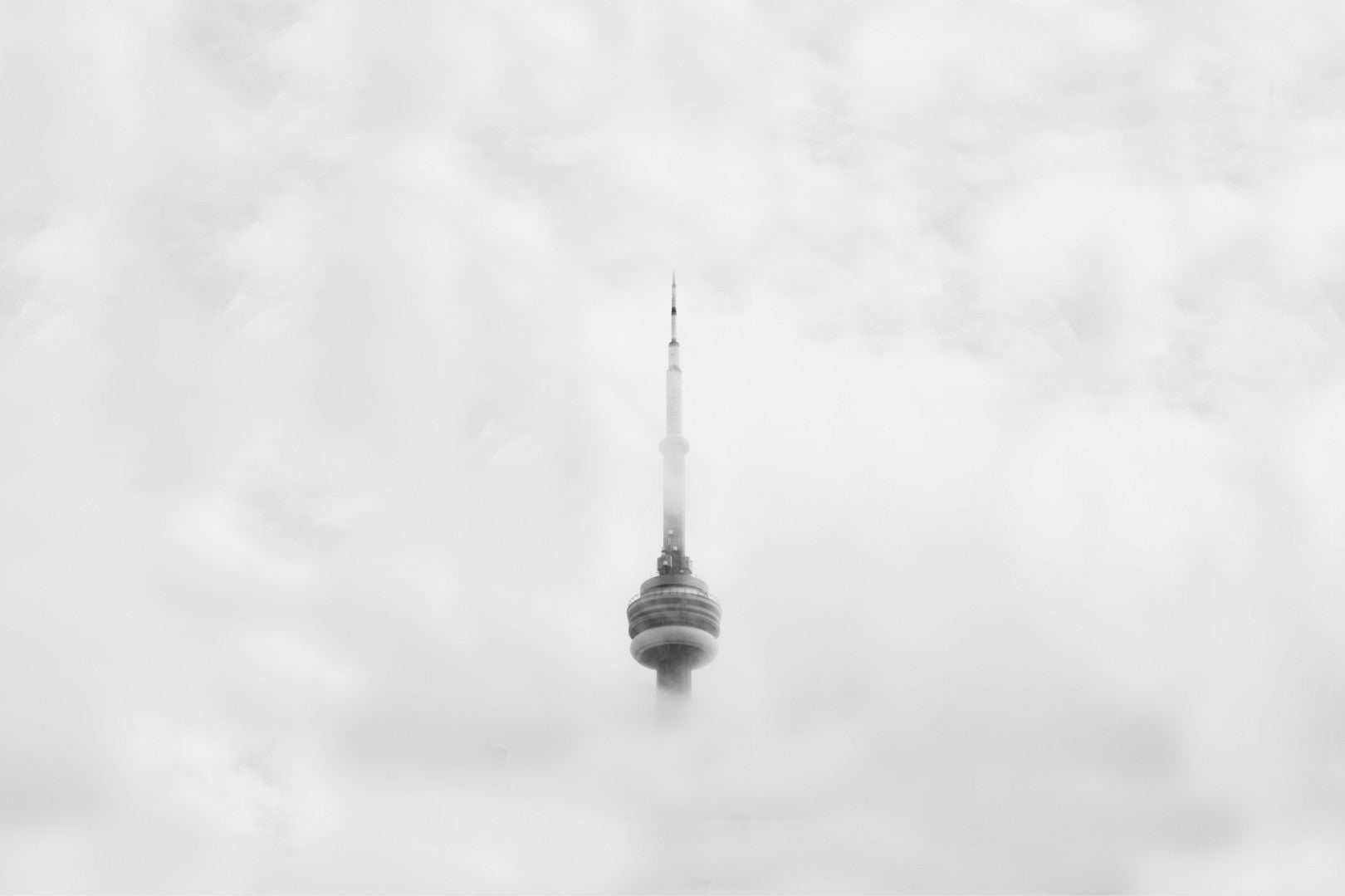 Cool tall tower and spire appear to be floating in the clouds in this black and white photo.