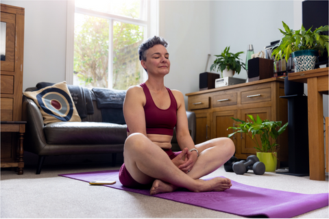 A woman practicing yoga on a mat in front of a couch.