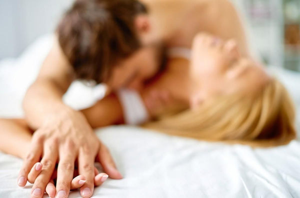 a man and woman kissing on a bed