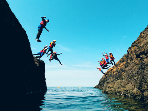 coasteering in north Wales jumping off rock into the blue sea