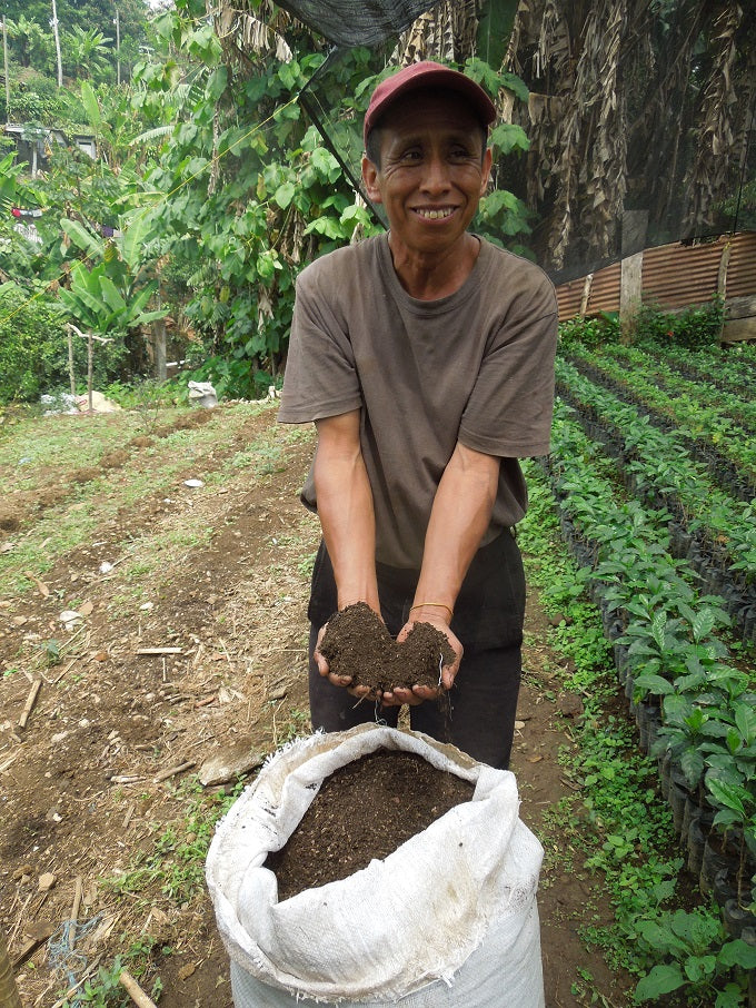 Farmer shows off healthy compost to fertilize nursery seedlings