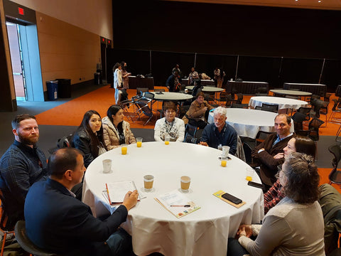 Eight people sitting around a table in a conference room, having a meeting.