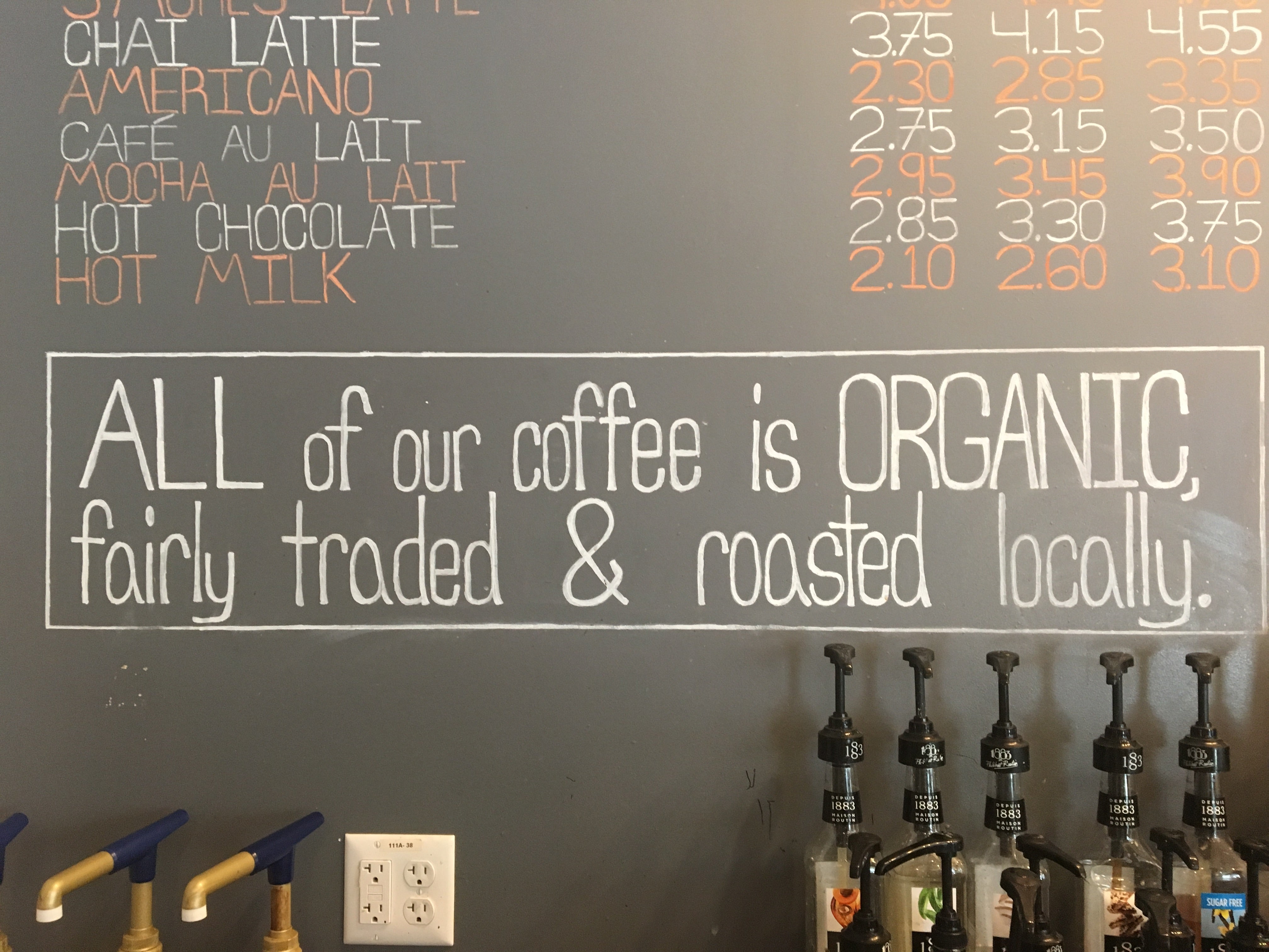 A chalkboard with the words "All of our coffee is organic, fairly traded & roasted locally" written on it