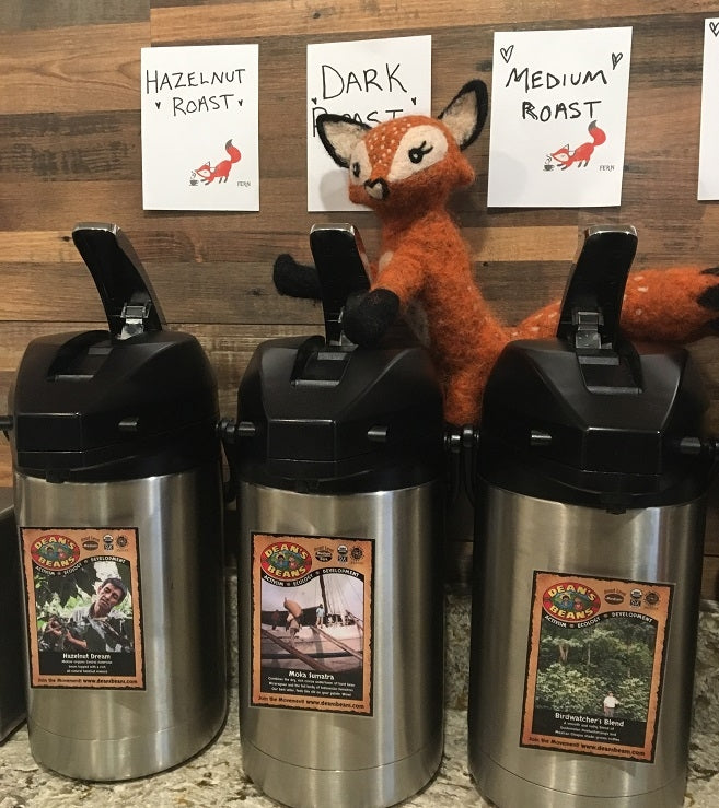 Three coffee pots with a fox stuffed animal placed on top