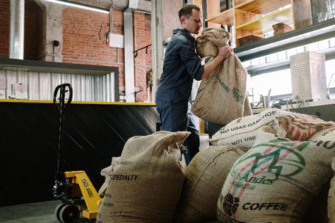 coffee roaster moving sack of green coffee