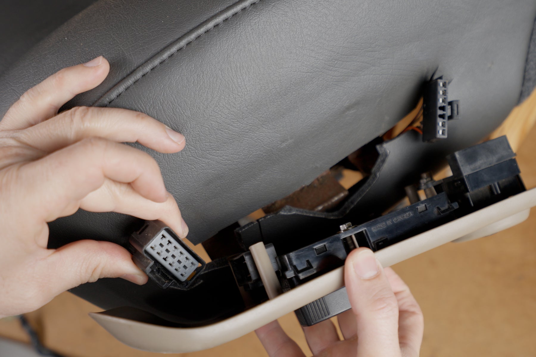 a photo displaying someone plugging their power controls back into their seat control bezel