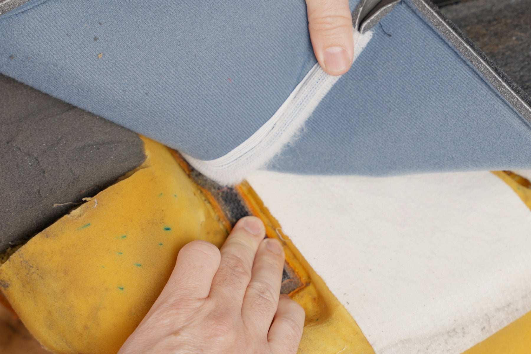 a photo displaying someone carefully separating the velcro connecting a seat cover and a foam cushion