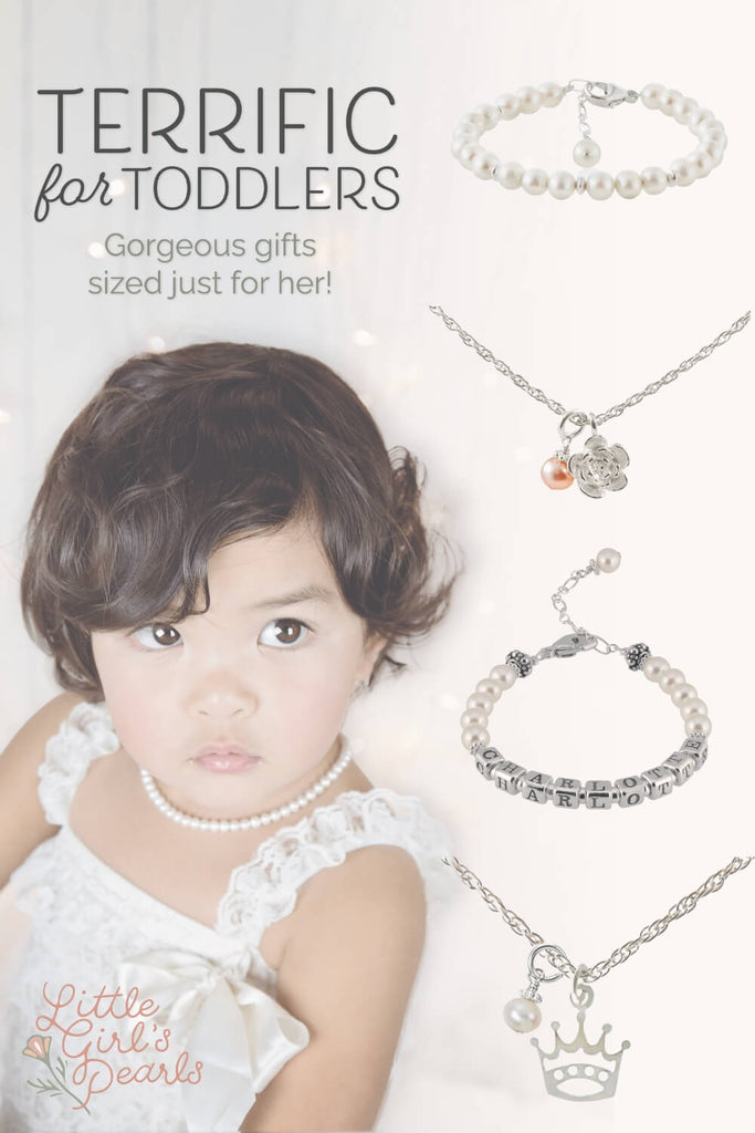 Little girl in white lace jumper with satin bow, wearing a little girl's pearls sweet pearl necklace, amidst twinkling Christmas lights.