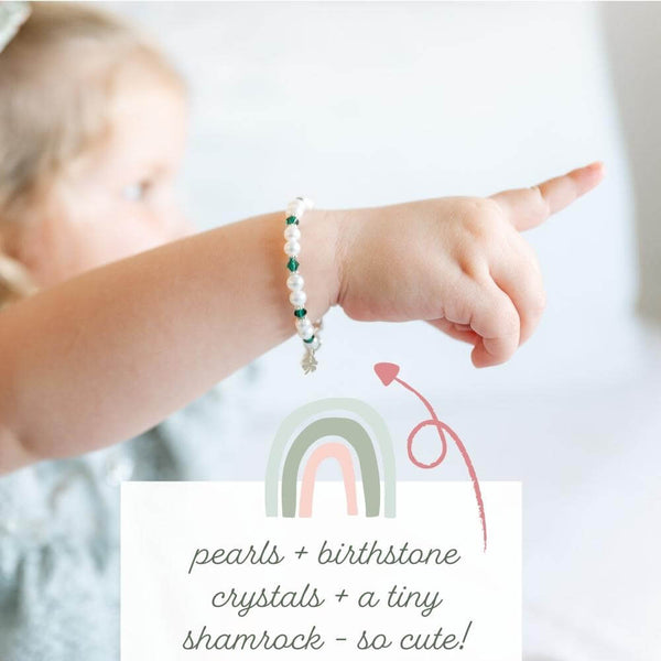 little girl wearing a pearl bracelet with her birthstone crystal and a tiny four-leaf clover charm.