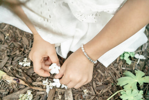 Little girl picking flowers with pearl bracelet. 
