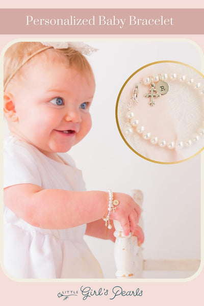 Baby girl wearing a christening gown and a personalized baptism bracelet in pearls.
