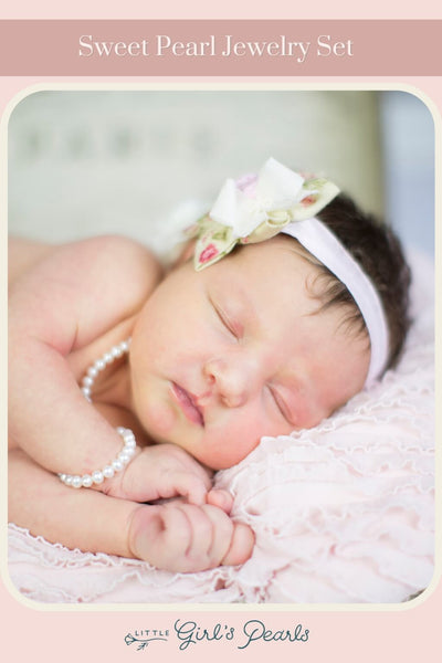 sleeping baby on a pink blanket wearing a sweet pearl necklace and bracelet.