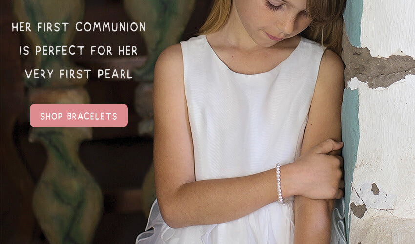 Little girl wearing a pearl bracelet for her Catholic first holy communion occasion.