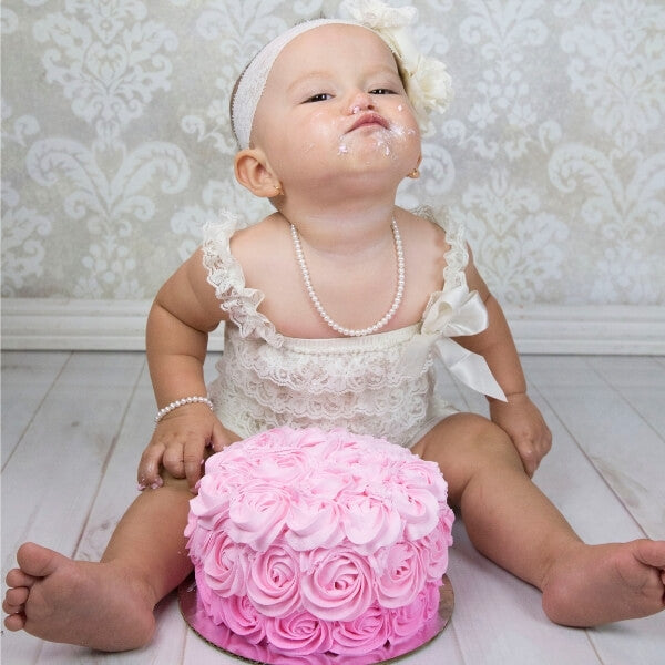 Girl's first birthday pink cake smash wearing pearl necklace