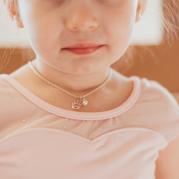 Little girl wearing pink leotard and necklace with pearl and crown