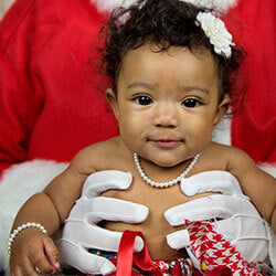 Toddler Girl wearing Little Girl's Pearls necklace being held by Santa for Christmas.