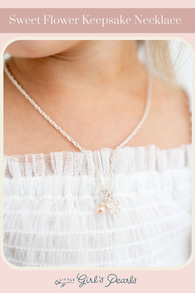 little girl in a lace dress wearing a sweet flower keepsake necklace with pearls.