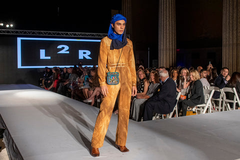 Karan model in desert overall and blue head scarf and blue cross body leather bag